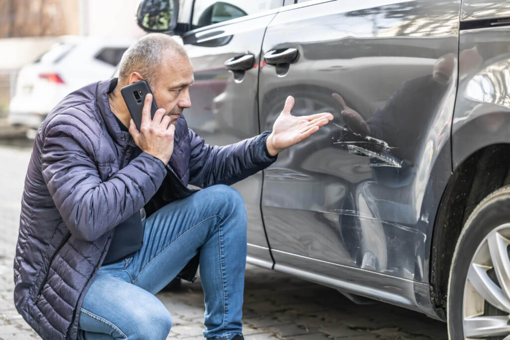 Personne regardant sa voiture après un léger accrochage sur un parking