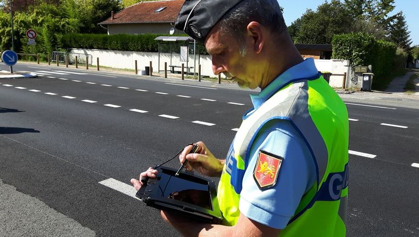 Gendarme utilisant une tablette pour un PV électronique, expliquant pourquoi la signature du contrevenant n'est pas obligatoire.