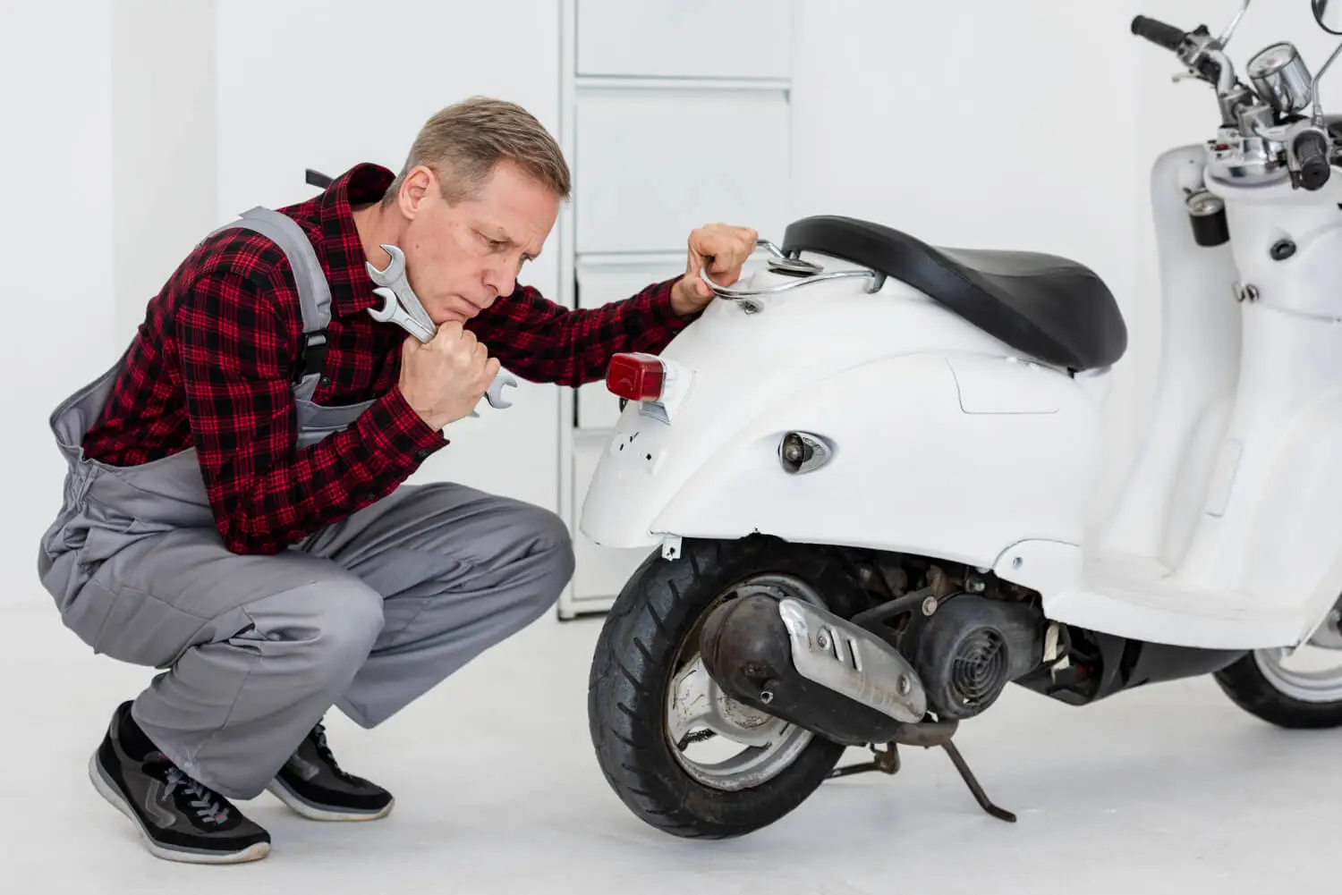 garagiste qui examine un scooter en panne