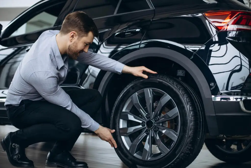 Roue de voiture bloquée, illustrant les causes possibles comme un étrier de frein grippé ou un frein à main collé.