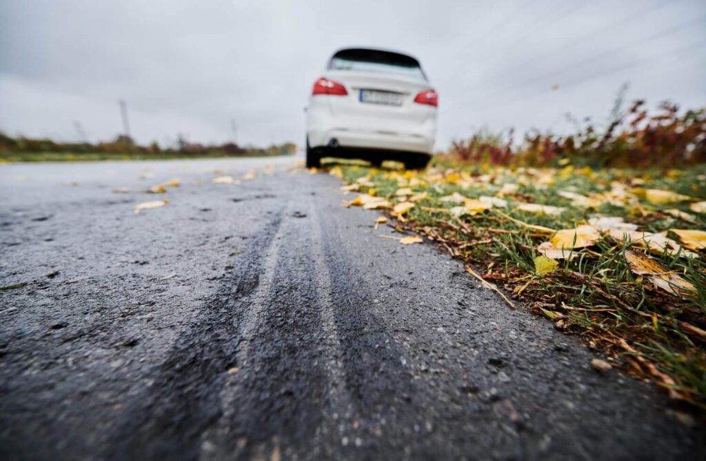 Voiture avec des traces de dérapage, illustrant le danger d'une roue arrière qui se bloque en roulant.