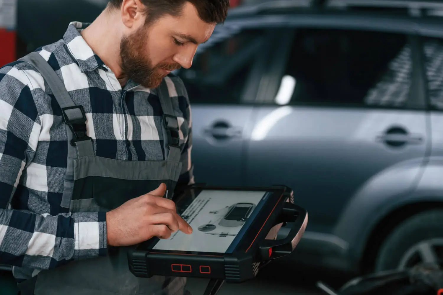 Garagiste qui tient une valise de diagnostic automobile affichant un message d'erreur lors de la tentative d'effacement d'un code défaut.