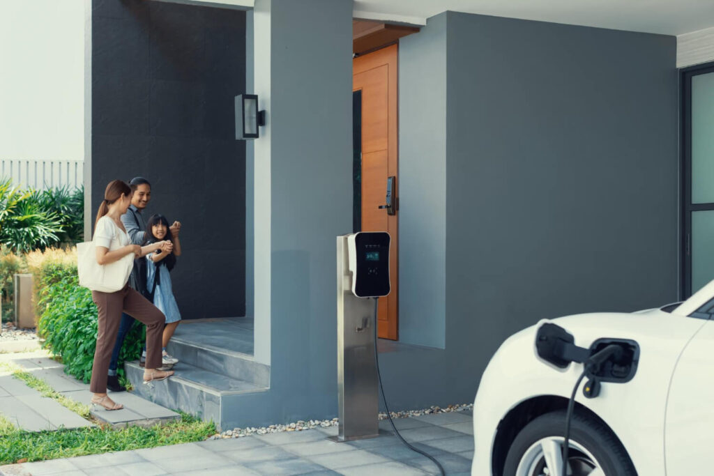 Une voiture hybride rechargeable branchée à une borne de recharge domestique dans un garage.