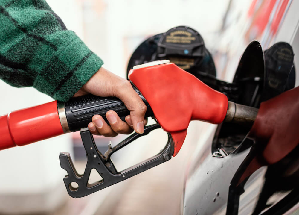 Pistolet de carburant essence (sans plomb) positionné au-dessus d'une trappe à carburant diesel, avec un signe d'interdiction.