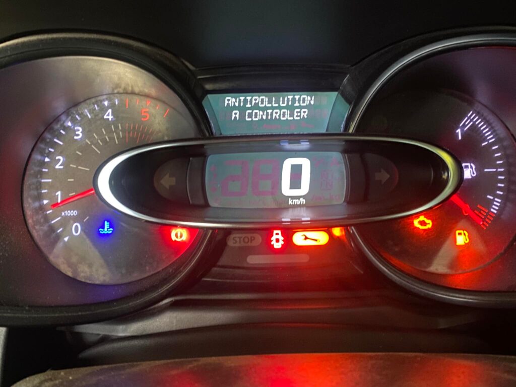 Tableau de bord d'une Renault Clio 4 avec le voyant bleu de température du liquide de refroidissement allumé.