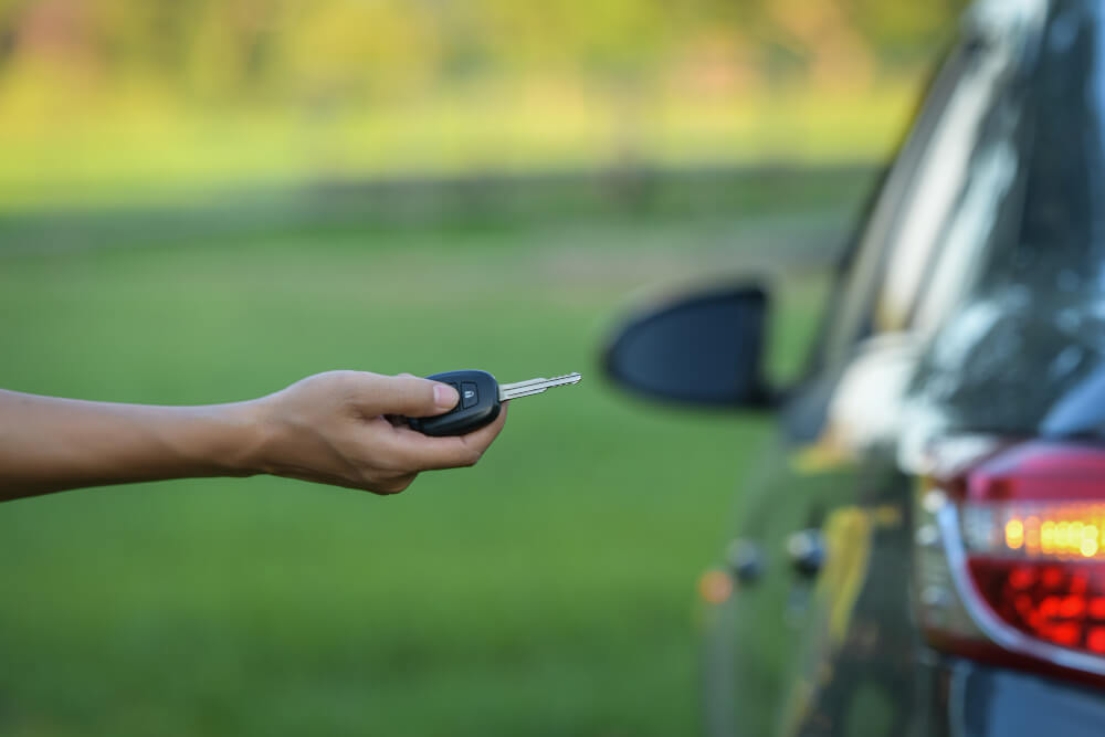 La centralisation de ma Clio 3 ne fonctionne plus : que faire ? 2 Main tenant une clé (plip) de Renault Clio 3, pointée vers la voiture.