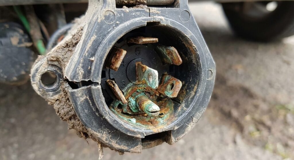 Prise de remorque 7 broches ouverte montrant des contacts oxydés responsables du retour de masse