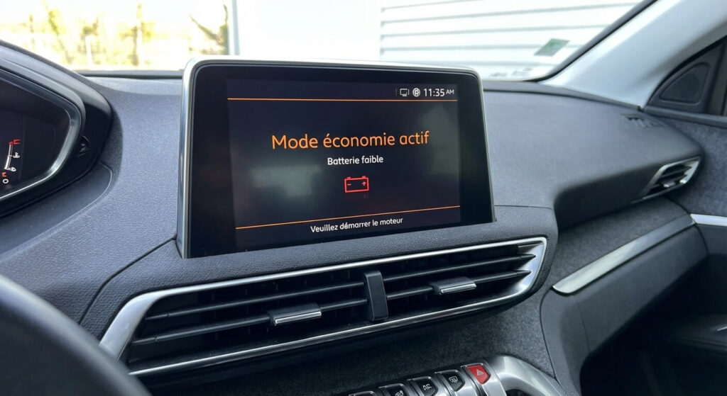 Écran central d'une Peugeot affichant le message Mode économie actif et batterie faible