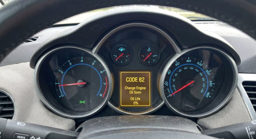 Écran central du combiné d'instruments d'une Chevrolet Cruze affichant le message "Code 82", indiquant que la durée de vie de l'huile moteur est à 0%