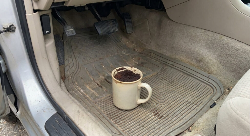 Comment enlever les odeurs de gasoil sur un vêtement ou dans une voiture ? 3 Tasse remplie de marc de café posée sur les tapis de sol d'une voiture pour absorber l'odeur de carburant