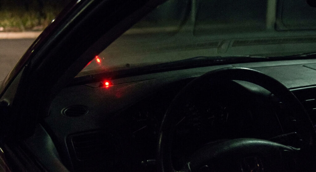 Vue rapprochée d'un petit voyant rouge clignotant sur le tableau de bord d'une voiture stationnée