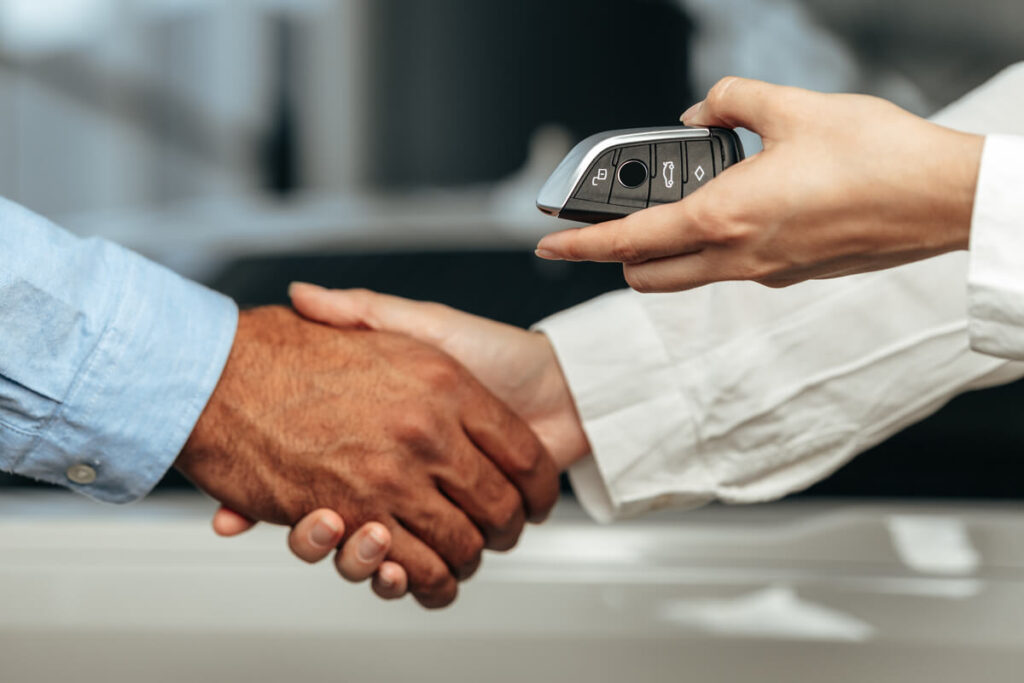 Poignée de main et échange de clés lors de la vente d'une voiture au juste prix du marché.