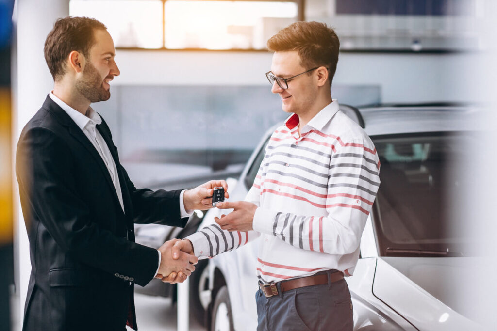 Devenir convoyeur d’automobile 3 Un convoyeur de véhicule remettant les clés d'une voiture neuve à son client après une livraison réussie.