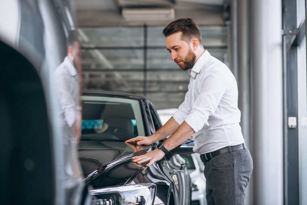 Un expert automobile contrôlant l'état d'un véhicule d'occasion avant de valider l'offre de rachat cash.