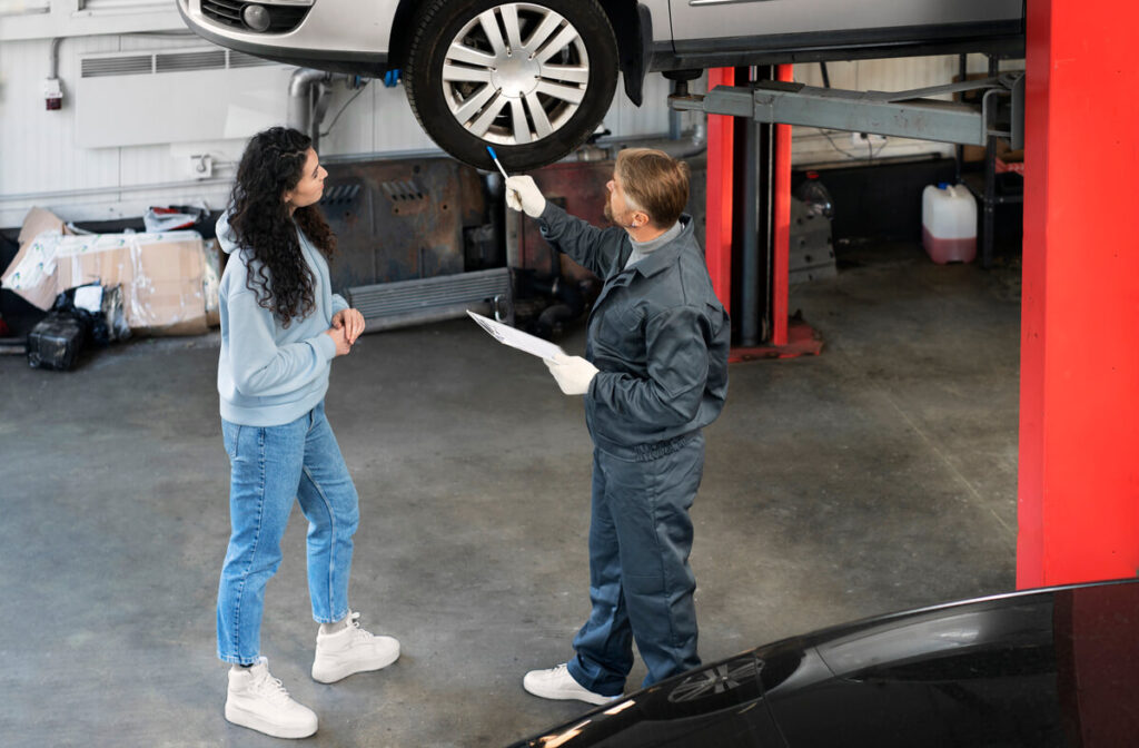 Un automobiliste examinant le devis de remplacement de ses quatre pneumatiques au comptoir d'un garage.