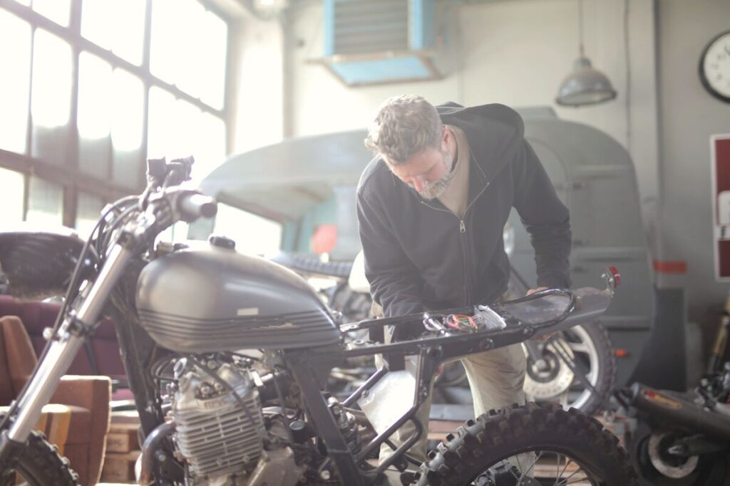 Un jeune mécanicien travaillant sur le moteur ouvert d'un scooter 50cc dans un atelier.