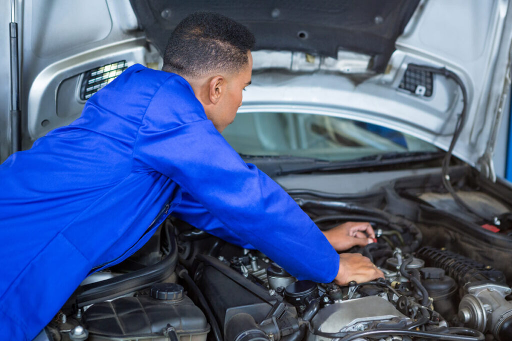 Un mécanicien examinant le compartiment moteur d'une voiture citadine française.