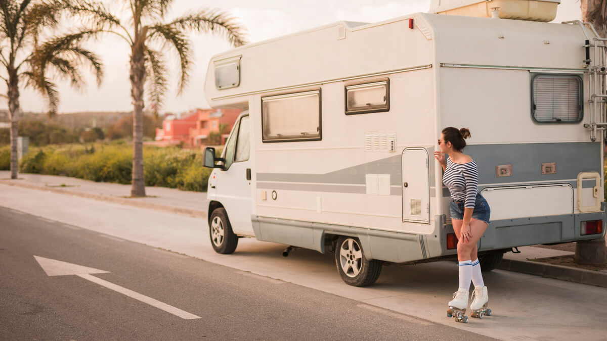 Un camping-car circule sereinement sur une route côtière ensoleillée.