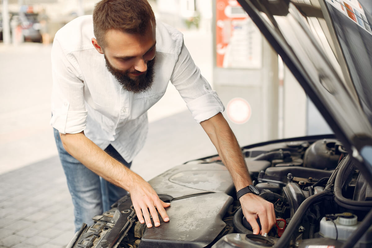 Automobiliste vérifiant le niveau d'huile moteur avec la jauge sous le capot de sa voiture.
