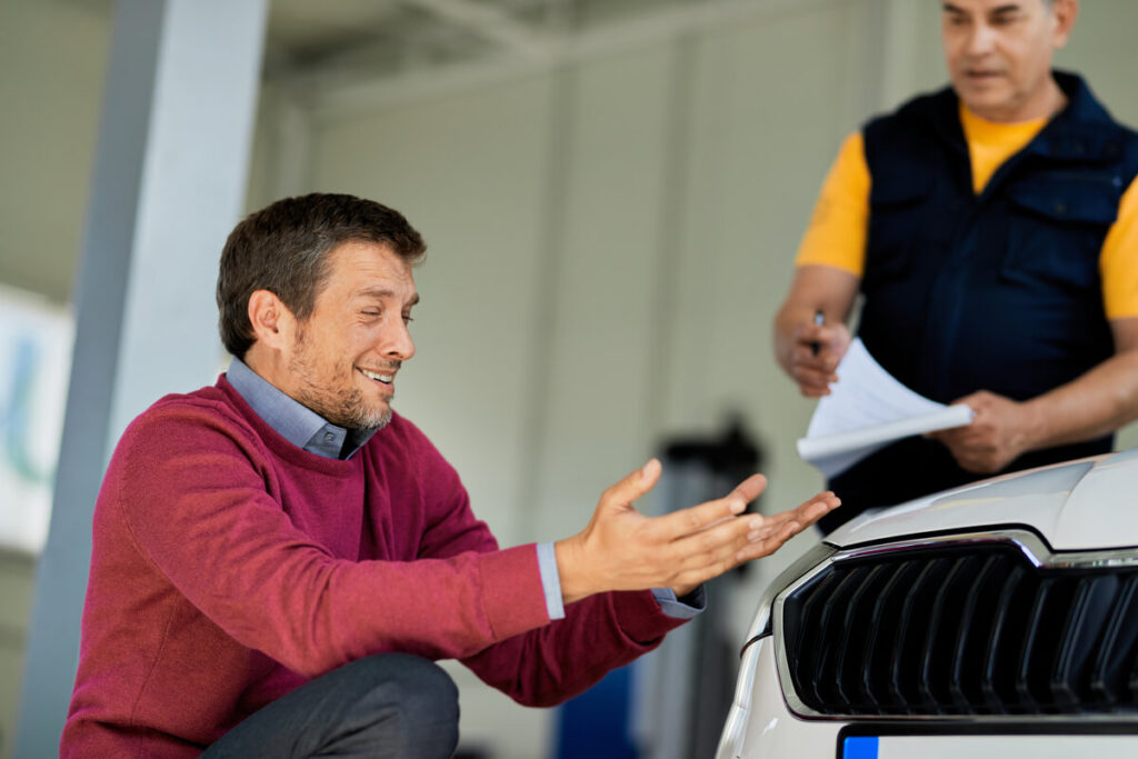 Voiture d'occasion en panne après achat chez un professionnel : vos recours 2 Client discutant avec un vendeur de voiture d'occasion devant une voiture en panne.