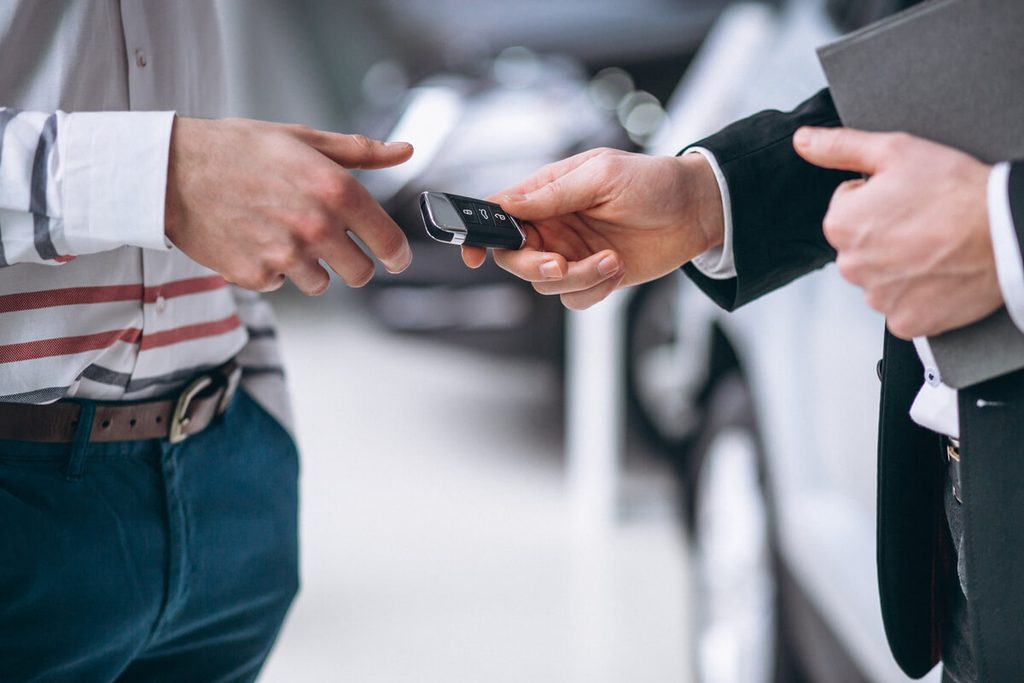 Propriétaire tendant les clés de sa voiture à l'acheteur lors de la vente du véhicule.